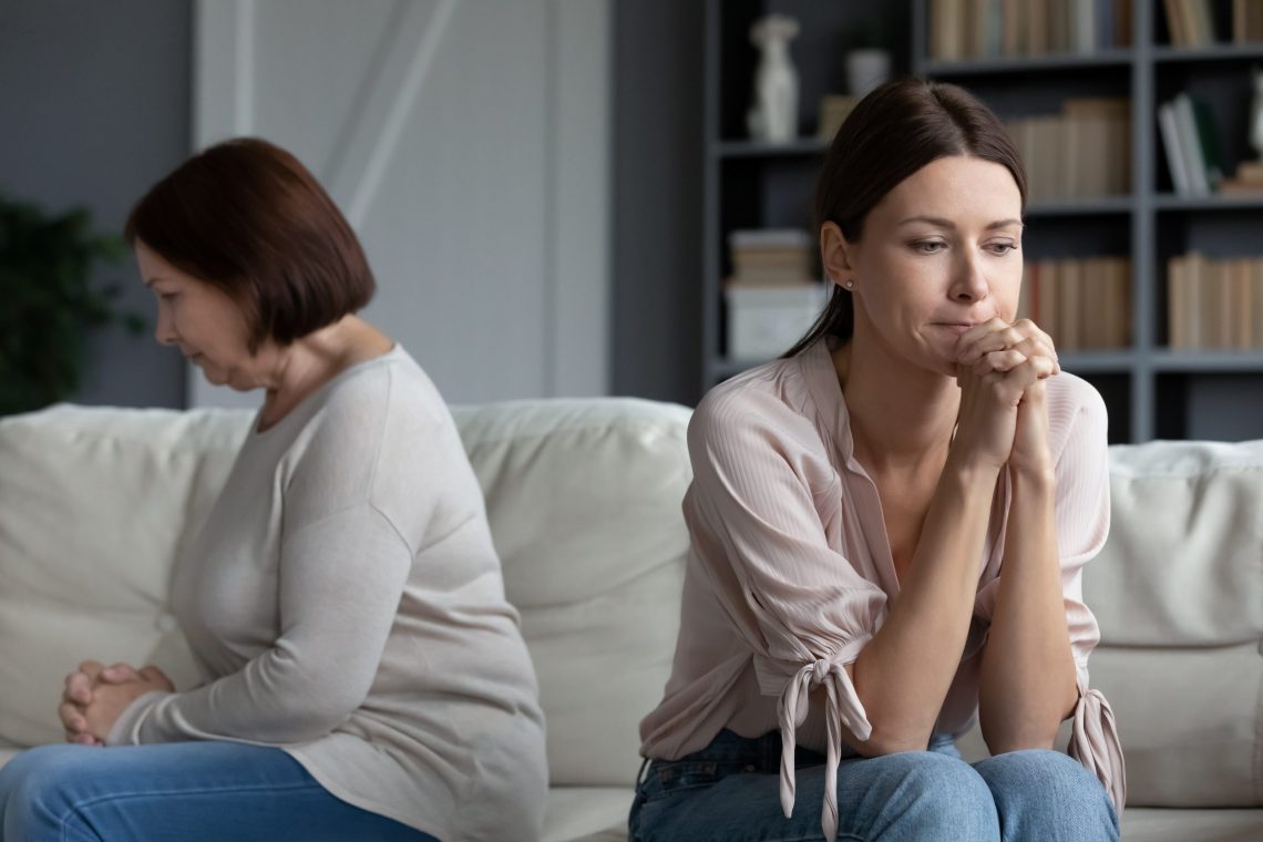 after quarrel silent daughter sitting aside of middle aged mother