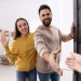 happy couple welcoming their guest near door. invitation to come indoors