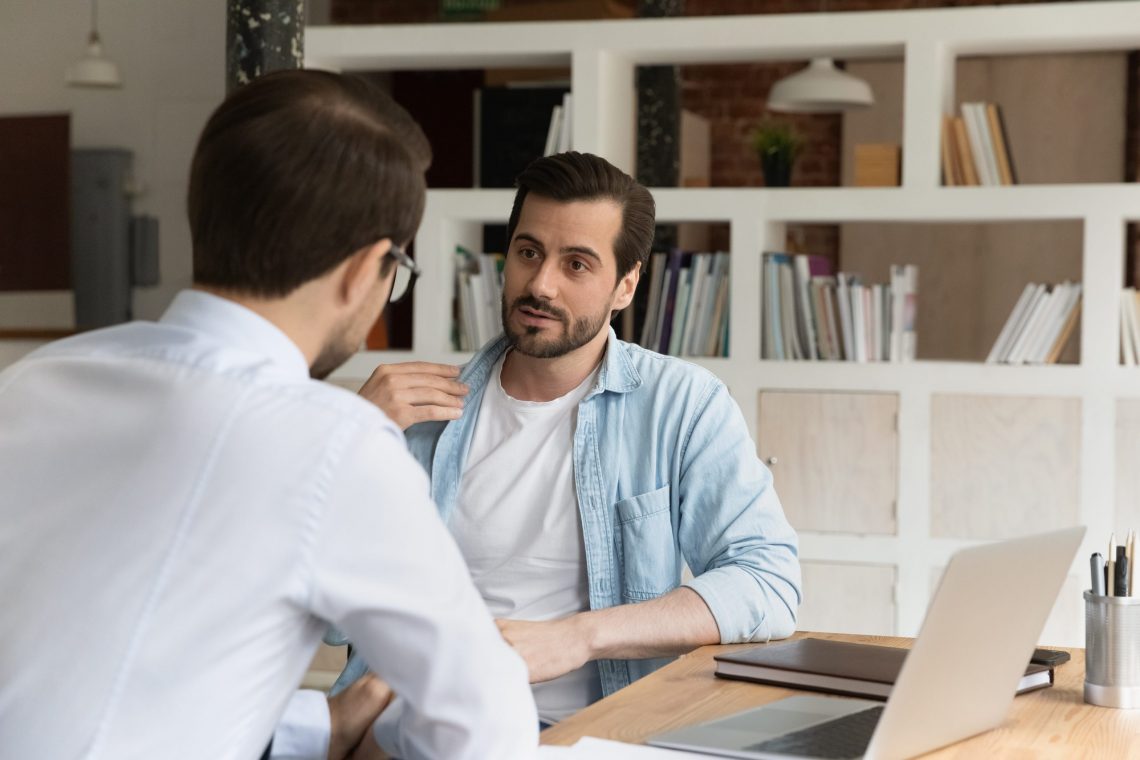 businesspeople male staff members talking sit at workplace desk